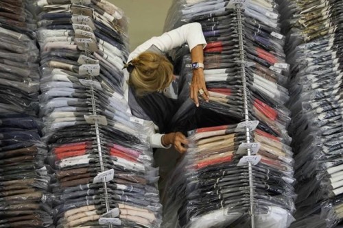 Nadia Zanola, chairman of the 'Cose di Maglia' factory, goes through racks of clothing at a warehouse section of unsold clothes, in Brescia, Italy, Tuesday, June 14, 2022. Small Italian fashion producers are still allowed to export to Russia, despite sanctions, as long as the wholesale price is under 300 euros. But they are having a hard time getting paid, due to restrictions tied to the financial sector. (AP Photo/Luca Bruno)