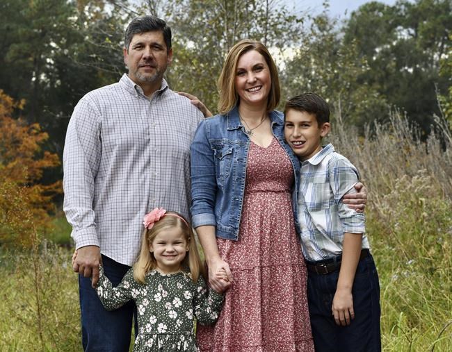 Reda Hicks appears with her husband Jake Hicks, left, daughter Katie and son Howard in Houston on Nov. 21, 2021. Reda Hicks, 41, was born and raised in Odessa, the epicenter of the West Texas oil industry. Her family is large, conservative and deeply evangelical. Her move to Austin for college was an eye opener. She has watched friction among friends and family from her two very different worlds devolve on her social media feeds. (Alicia Verdier via AP)