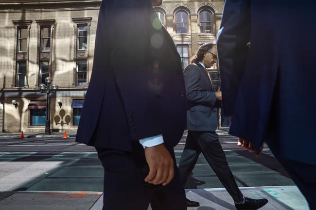 A growing swath of Canadian companies are no longer requiring employees to be vaccinated to come to work, as corporate policies ease in step with public health guidelines. A group of men walk along Wellington Street in the financial district in Toronto on Wednesday, September 29, 2021. THE CANADIAN PRESS/Evan Buhler