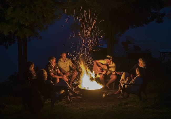 The Hanavan family and friends enjoy a camp fire on the shore of Shadow Lake near Coboconk, Ont., Saturday, Aug. 8, 2021. Though health restrictions have lifted, some summer camp operators say they're grappling with staffing issues related to the COVID-19 pandemic. THE CANADIAN PRESS/Fred Thornhill