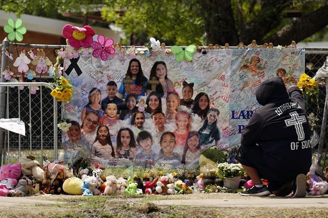 FILE - A mourner stops to pay his respects at a memorial at Robb Elementary School, created to honor the victims killed in the recent school shooting, June 9, 2022, in Uvalde, Texas. Two teachers and 19 students were killed in the mass shooting. Law enforcement authorities had enough officers on the scene of the Uvalde school massacre to have stopped the gunman three minutes after he entered the building, the Texas public safety chief testified Tuesday, June 21 pronouncing the police response an “abject failure.”(AP Photo/Eric Gay, File)