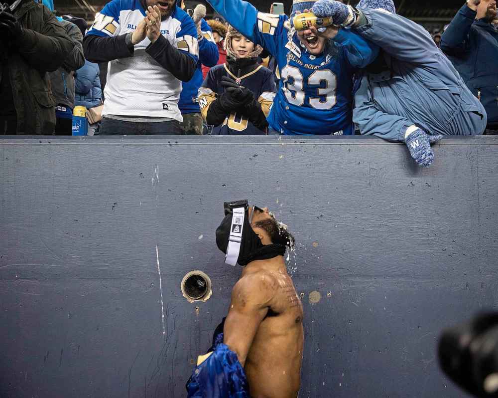 Fans pour beer in Bombers player Rasheed Bailey’s mouth during Grey Cup celebrations at IG Field. (Jessica Lee / Winnipeg Free Press)