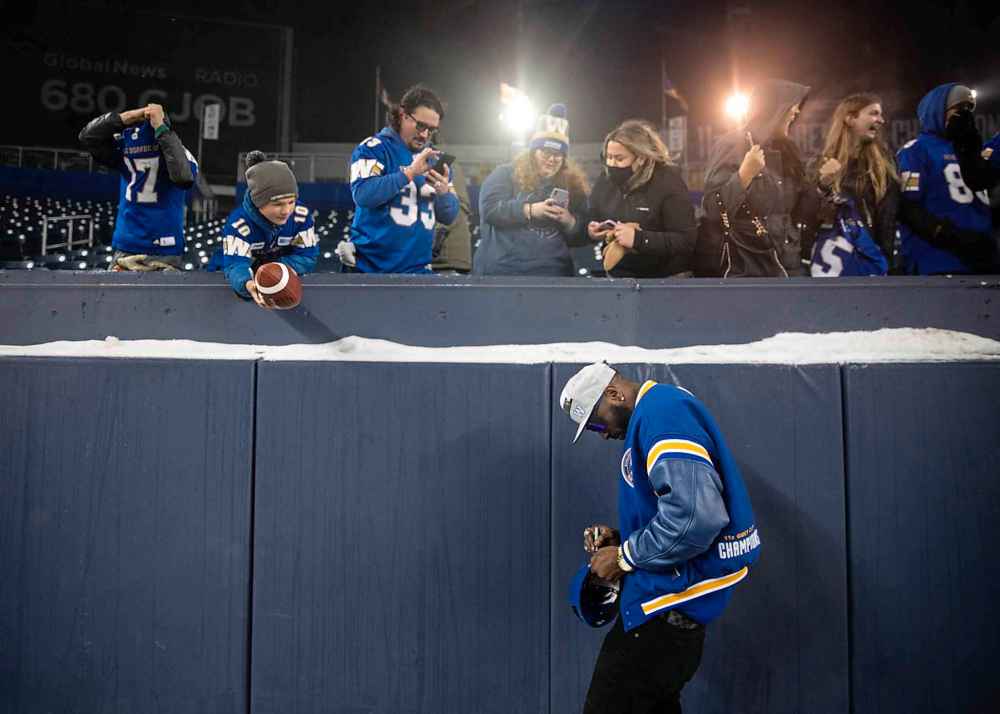 Bombers player Willie Jefferson signs fans keepsakes while celebrating the recent Grey Cup victory at IG Field. (Jessica Lee / Winnipeg Free Press)