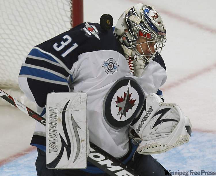 Winnipeg Jets goaltender Ondrej Pavelec gets the puck in the helmet during first-period action. (Joe Bryksa / Winnipeg Free Press)