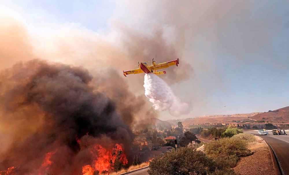An air tanker drops water on a fire in Simi Valley, Calif., Monday. (Ringo H.W. Chiu / The Associated Press)