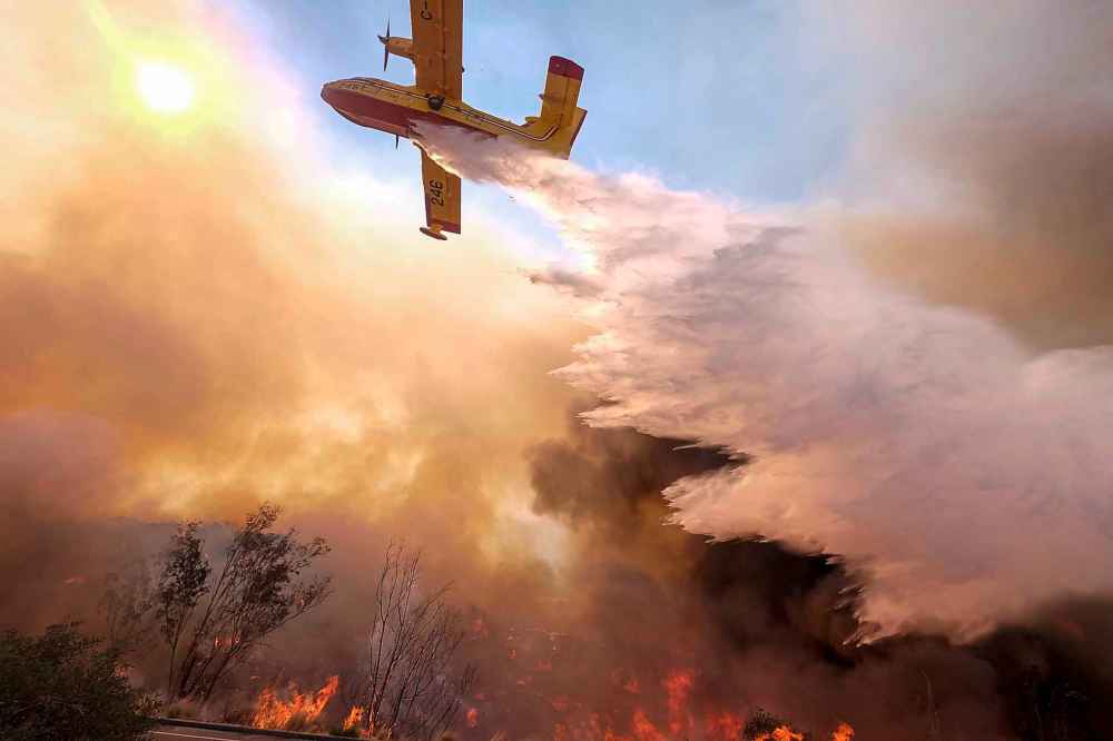 An air tanker drops water on a fire along the Ronald Reagan Freeway. (Ringo H.W. Chiu / The Associated Press)