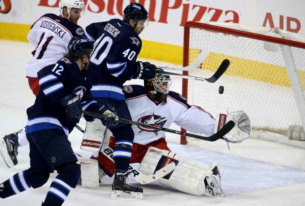 Trevor Hagan / Winnipeg Free Press
Columbus Blue Jackets' James Wisniewski (21) and Winnipeg Jets' Olli Jokinen (12) look on as Devin Setoguchi (40) tries to bat the puck past goaltender Curtis McElhinney (31) during the first period Saturday. McElhinney made the circus save.