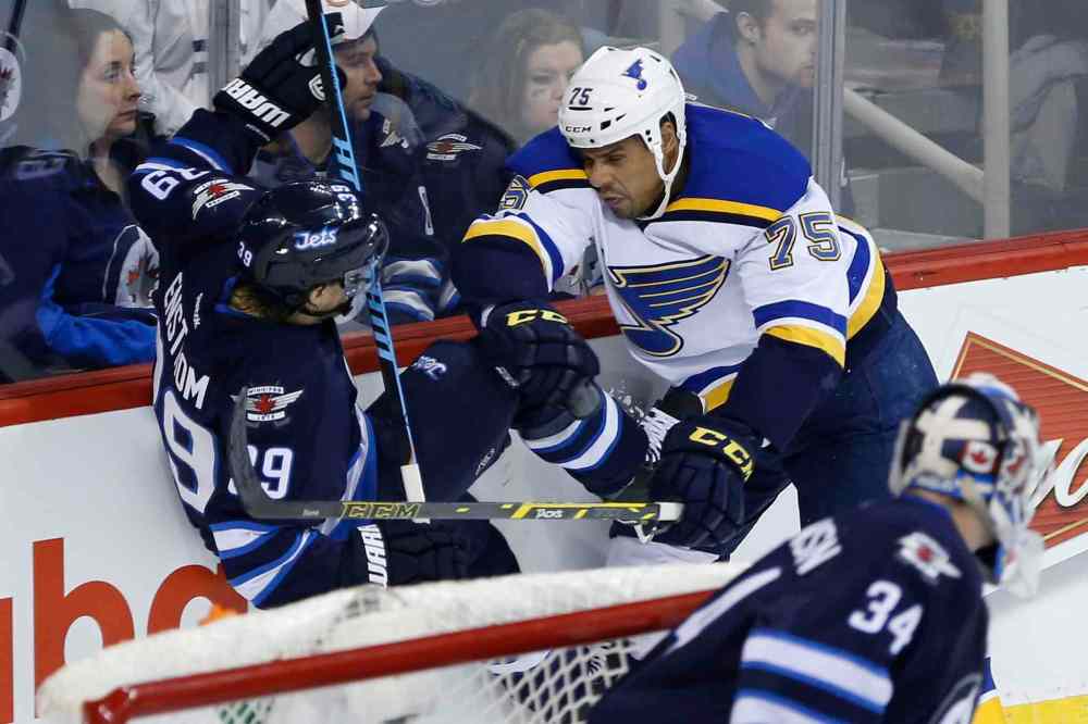 John Woods / The Canadian Press
Winnipeg Jets' Toby Enstrom (39) gets checked by St. Louis Blues' Ryan Reaves (75) as Jets goaltender Michael Hutchinson (34) looks on during second period.