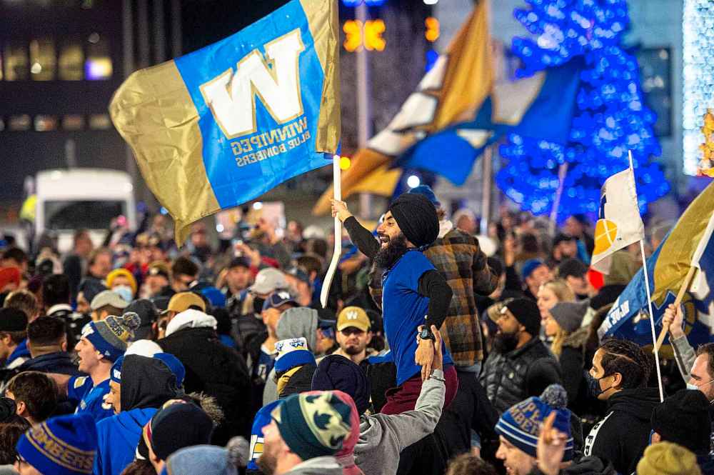 A Blue Bombers fan flies a Bomber flag while on top the shoulders of another fan Sunday evening as hundreds of fans at Portage and Main to celebrate the Bombers' second consecutive Grey Cup Championship title. (Mike Sudoma / Winnipeg Free Press)