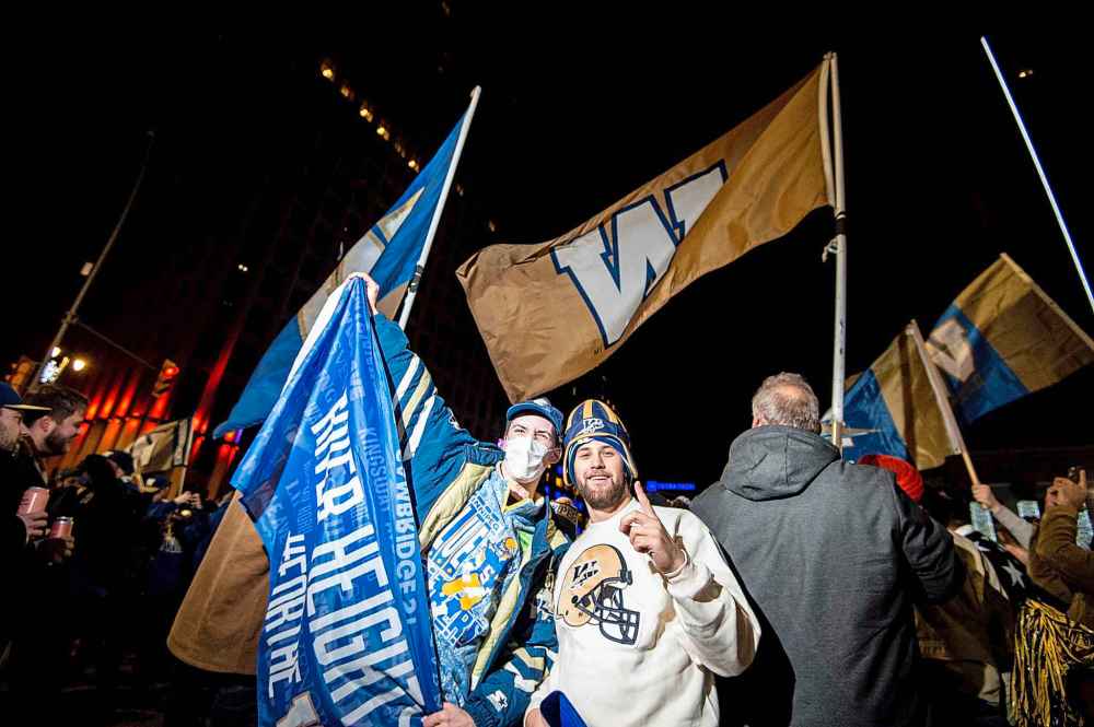 Mackinley Hall (left) and Ethan Nagler hold up a Blue Bomber banner as fans young and old celebrate the team's championship win. (Mike Sudoma / Winnipeg Free Press)