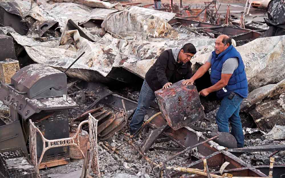 Santos Alvarado (right) and his son Ricky recover a safe deposit box from their destroyed home at Seminole Springs Mobile Home Park, Sunday in Agoura Hills, Calif. (Chris Pizzello / The Associated Press)