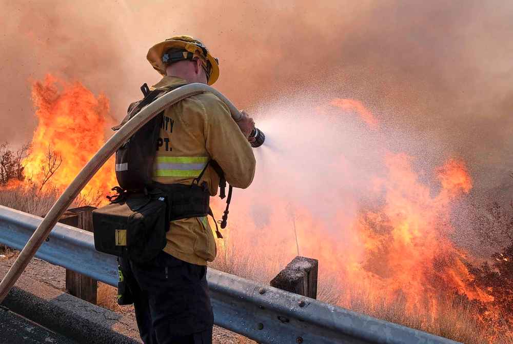 A firefighter battles a fire along the Ronald Reagan Freeway in Simi Valley, Calif., Monday. (Ringo H.W. Chiu / The Associated Press)