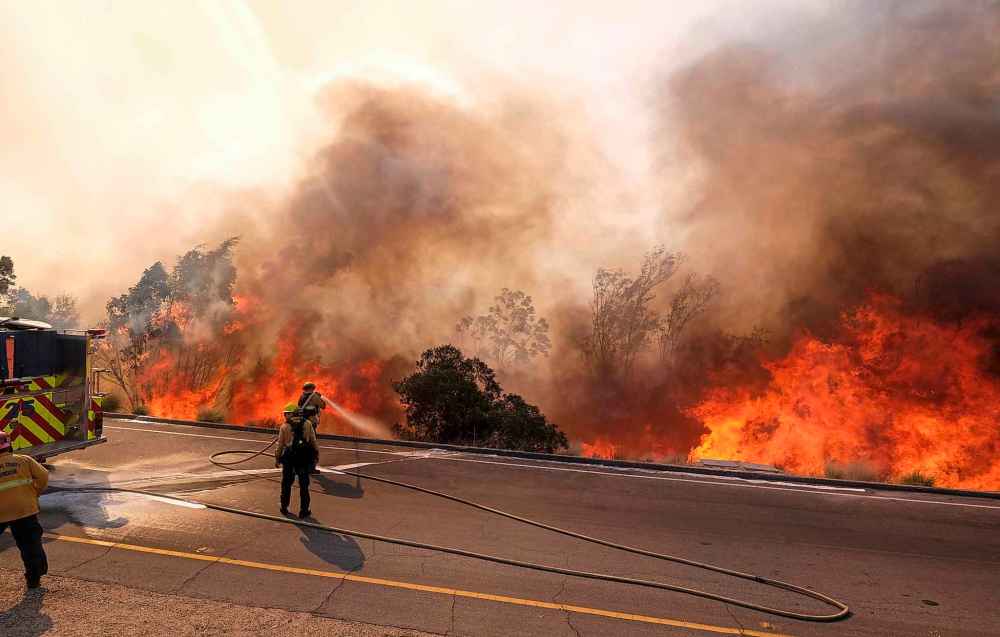A firefighter battles a fire along the Ronald Reagan Freeway in Simi Valley, Calif., Monday. (Ringo H.W. Chiu / The Associated Press)