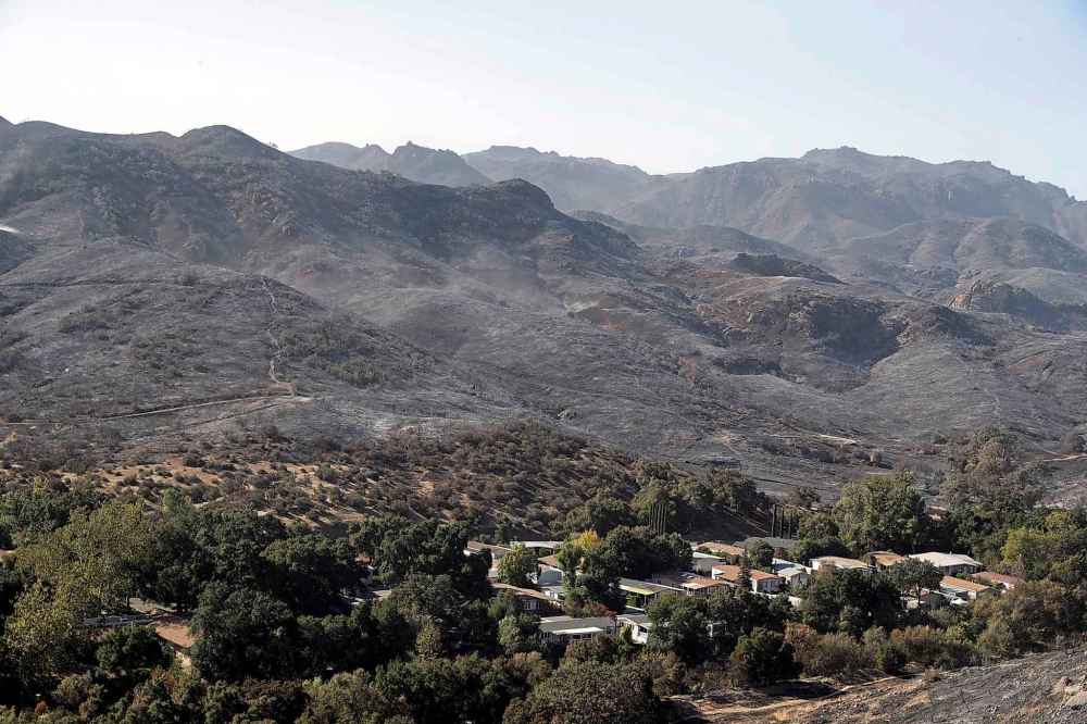 Burned out mountains tower over a residential neighborhood in the aftermath of a wildfire Monday in Westlake Village, Calif. (Marcio Jose Sanchez / The Associated Press)