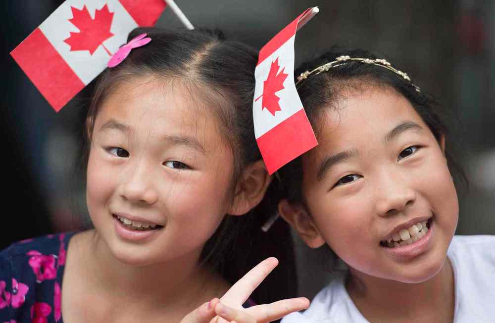 GRAHAM HUGHES / THE CANADIAN PRESS
Two girls smile as they watch the annual Canada Day parade in Montreal.