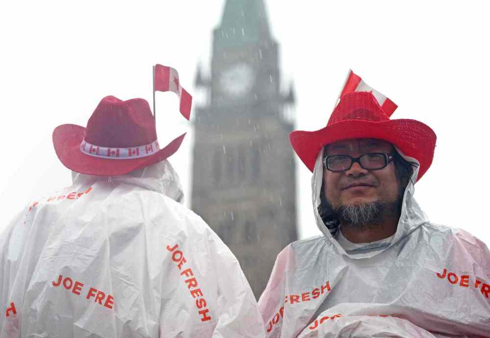 SEAN KILPATRICK THE CANADIAN PRESS
Two people stand outside in the rain on Parliament Hill during Canada 150 celebrations.