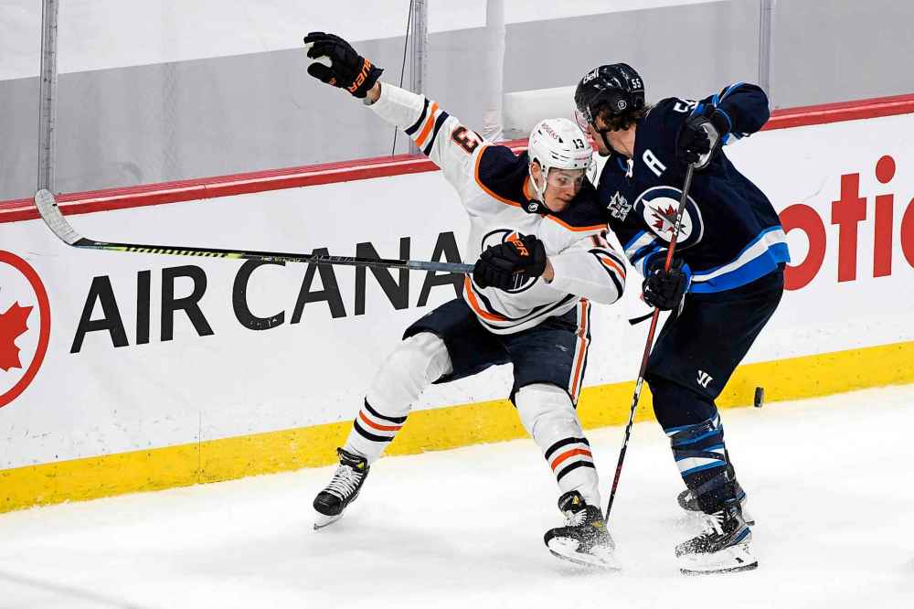 Mark Scheifele and Jesse Puljujarvi battle for the puck during the first overtime period. (Fred Greenslade / The Canadian Press)