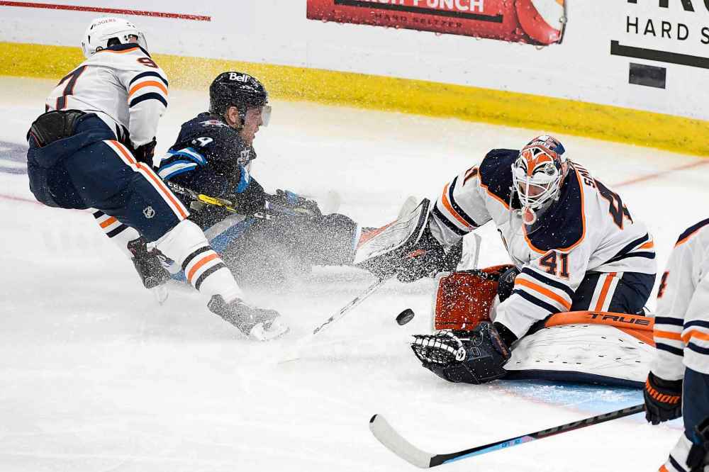 Goaltender Mike Smith makes a save as Andrew Copp is checked by Connor McDavid during the second period. (Fred Greenslade / The Canadian Press)