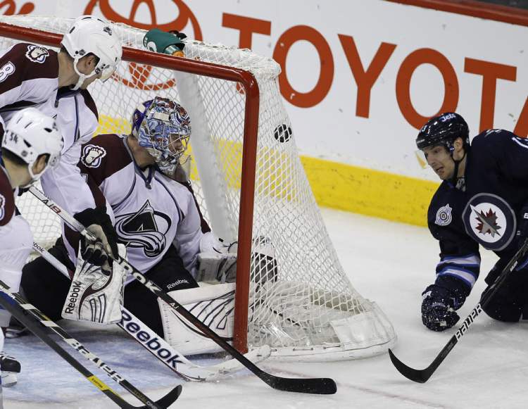 Winnipeg Jets' Kyle Wellwood (13) scores from behind the net on Colorado Avalanche's goaltender Semyon Varlamov.