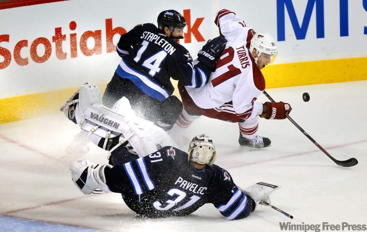 Phil Hossack / Winnipeg Free Press
Winnipeg Jet Tim Stapleton steers Pheonix's Kyle Turris and a bouncing puck away from sprawling Jet netminder Ondrej Pavelec Thursday at the MTS Centre.
