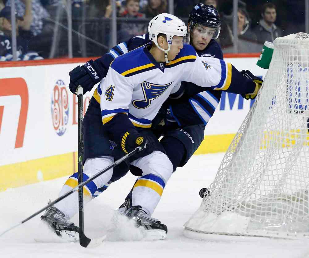 JOHN WOODS / THE CANADIAN PRESS
The Blues' Carl Gunnarsson and the Jets' Adam Lowry battle for the puck behind the Blues net during second-period NHL action.