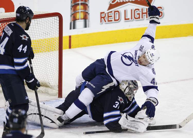JOHN WOODS / WINNIPEG FREE PRESS
Tampa Bay Lightning's Dana Tyrell goes over the top of Winnipeg Jets goaltender Ondrej Pavelec as Jets defenceman Zach Bogosian looks on during an NHL game in Winnipeg on Sunday.