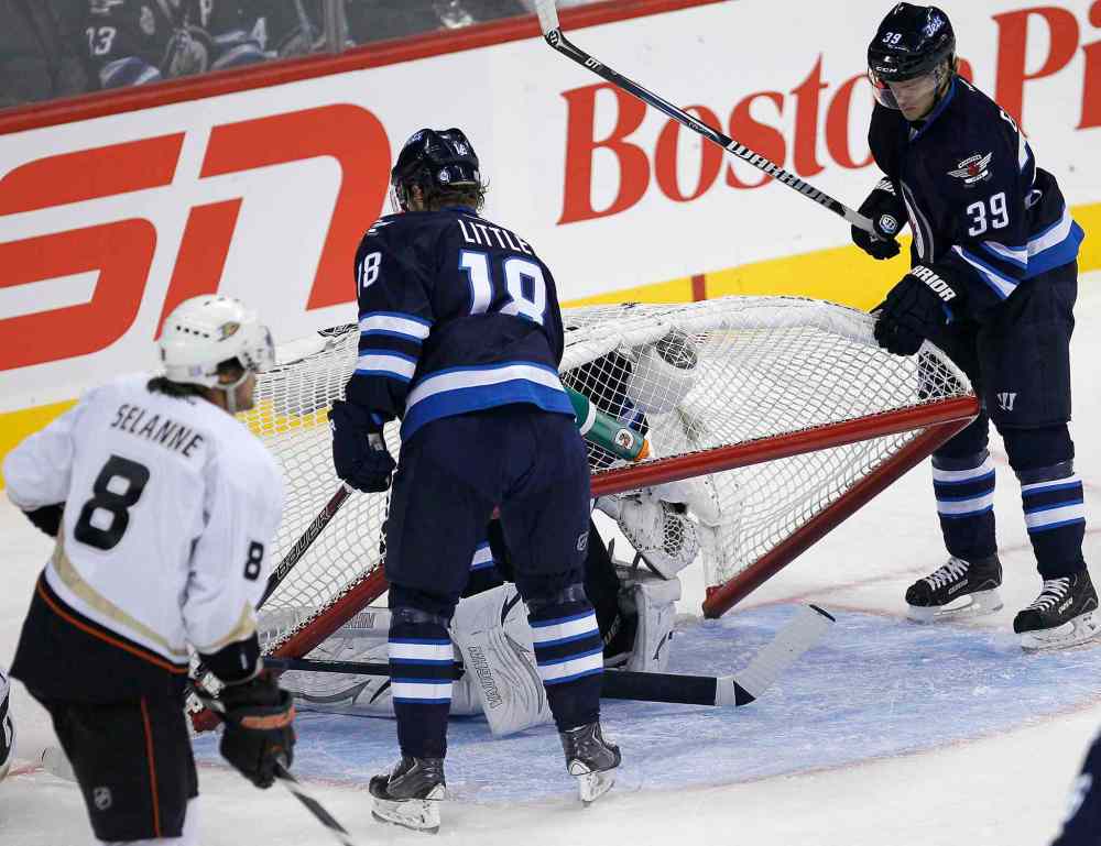 JOHN WOODS / WINNIPEG FREE PRESS
Winnipeg Jets' Bryan Little (18) and Toby Enstrom lift the net off goaltender Ondrej Pavelec in the first period as the Ducks' Teemu Selanne cruises past.