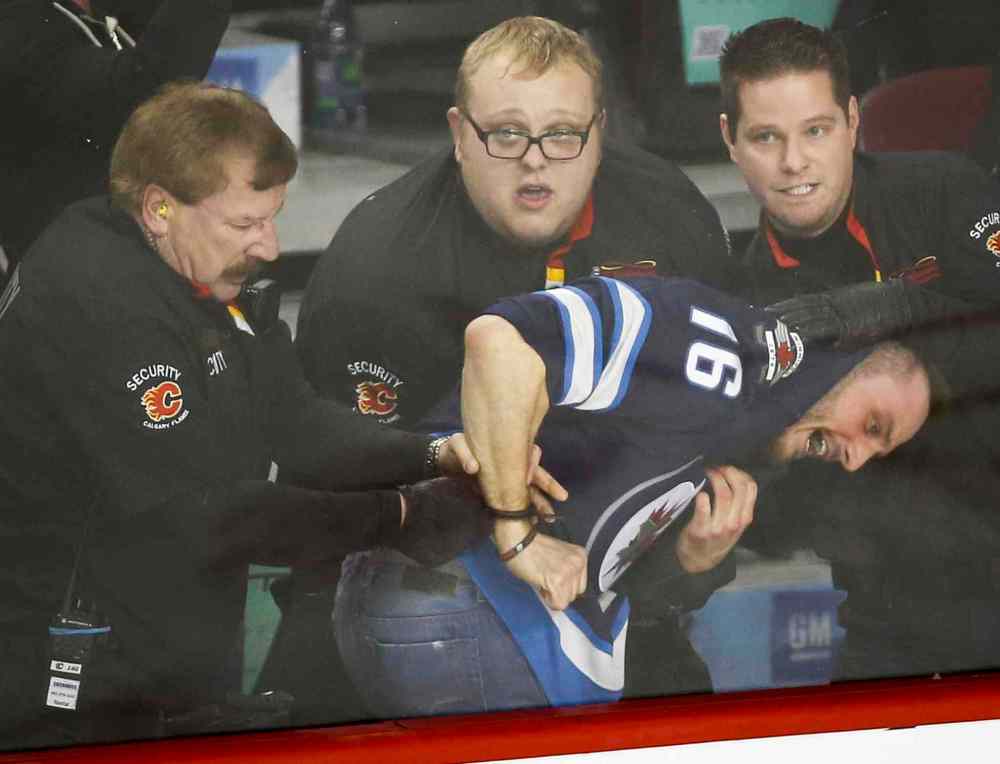 Jeff McIntosh / The Canadian Press
Security officials subdue and handcuff a Winnipeg Jets fan after a fight broke out during third period NHL hockey action against the Calgary Flames in Calgary Thursday. The Winnipeg Jets beat the Calgary Flames 5-2.