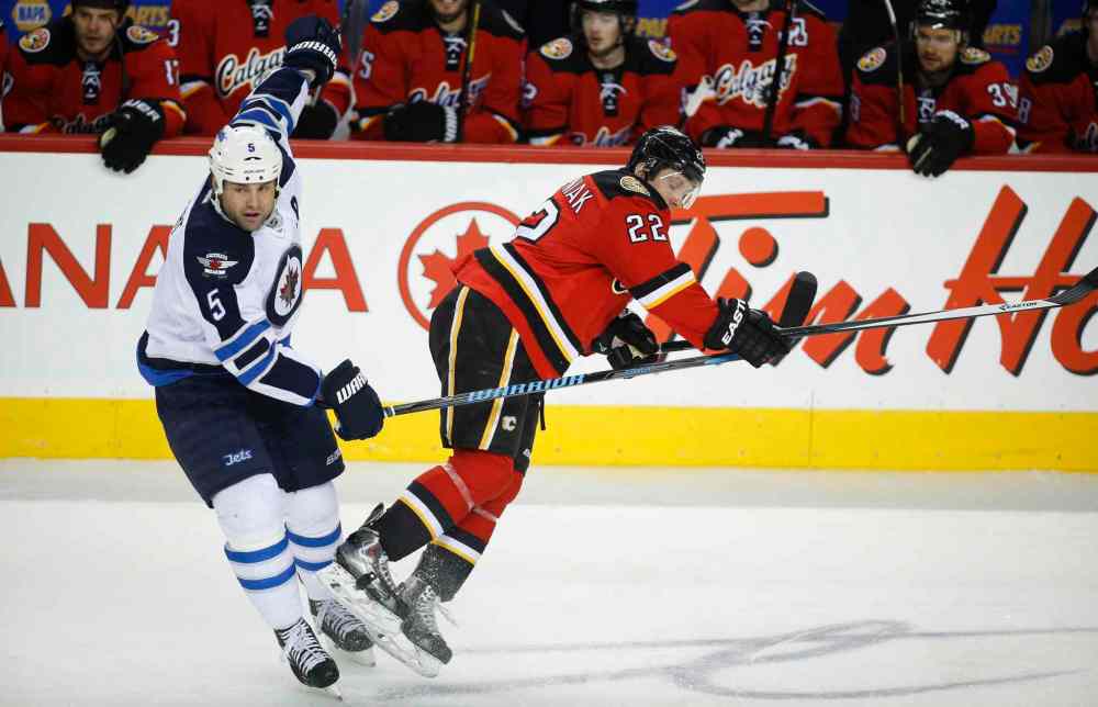 Jeff McIntosh / The Canadian Press
Winnipeg Jets' Mark Stuart, left, knocks Calgary Flames' Lee Stempniak to the ice during the first period.