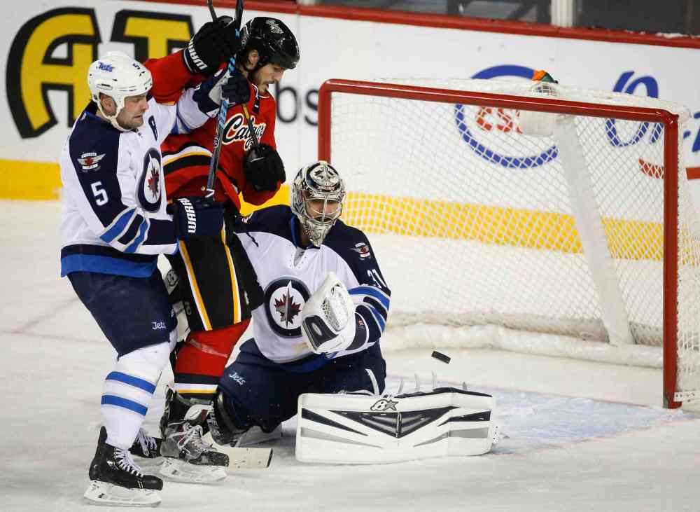 Jeff McIntosh / The Canadian Press
Winnipeg Jets' goalie Ondrej Pavelec, right, watches a rebound as teammate Mark Stuart checks Calgary Flames' Kevin Westgarth in the second period Thursday.