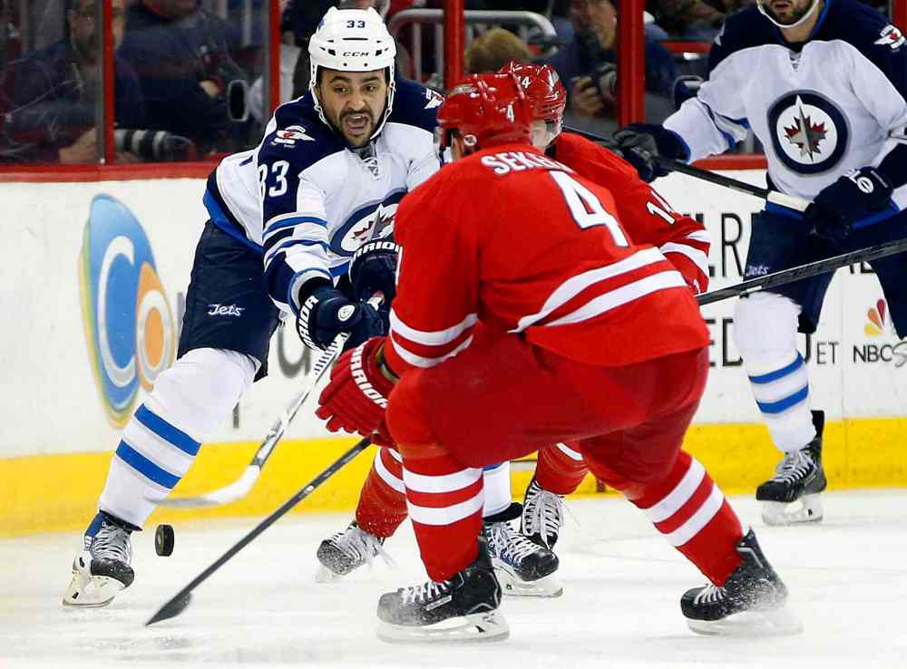 Karl B DeBlaker / The Associated Press
Winnipeg Jets' Dustin Byfuglien (33) tries to clear the puck past Carolina Hurricanes' Andrej Sekera (4) in the first period of Tuesday's hockey game.
