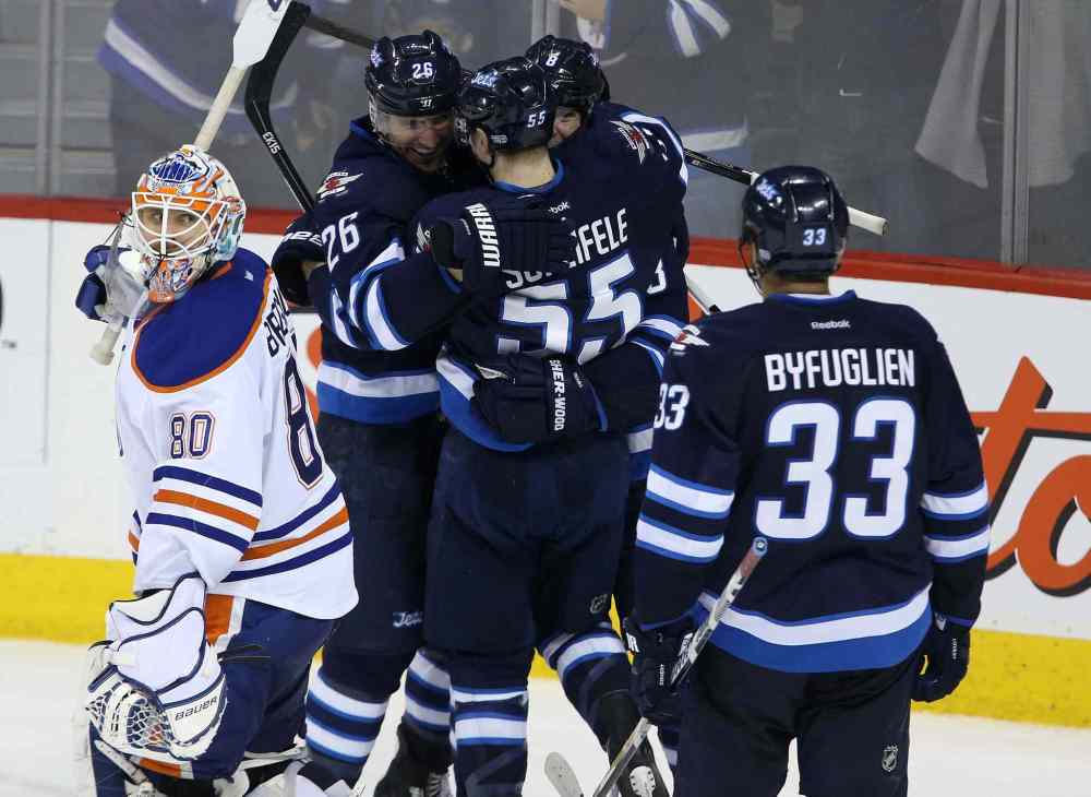 Trevor Hagan / Winnipeg Free Press
Edmonton Oilers' goaltender Ilya Bryzgalov (80) looks on as the Winnipeg Jets' Blake Wheeler (26), Mark Scheifele (55), Jacob Trouba (8) and Dustin Byfuglien (33) celebrate Trouba's game-winning goal in overtime to beat the Edmonton Oilers 3-2 in Winnipeg Saturday.