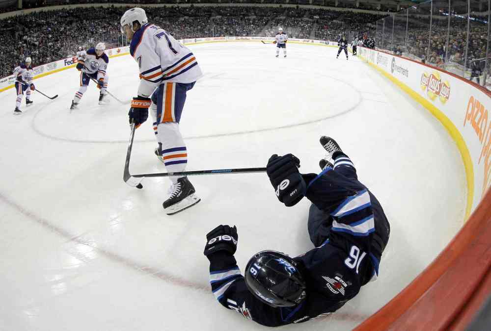 TREVOR HAGAN/WINNIPEG FREE PRESS
Edmonton Oilers' Anton Belov (77) takes down Winnipeg Jets' Andrew Ladd (16) in the second period of Saturday's NHL game at Winnipeg's MTS Centre.
