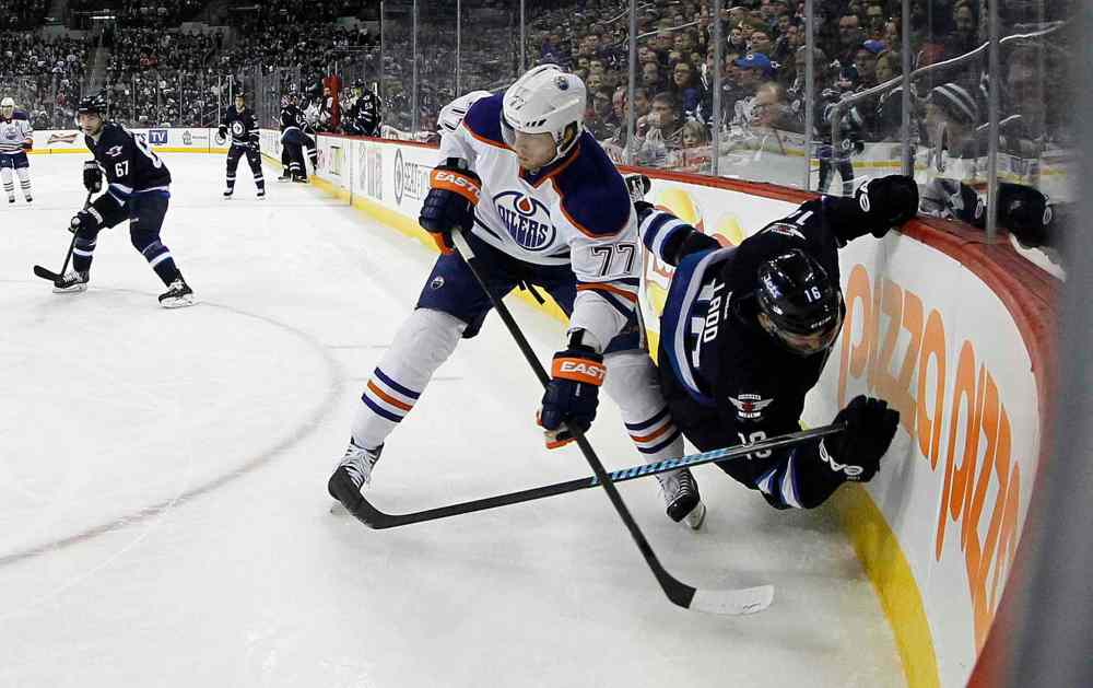 Trevor Hagan / Winnipeg Free Press
Winnipeg Jets' Andrew Ladd (16) clings to the boards after Edmonton Oilers' Anton Belov (77) takes him down during second period NHL hockey action at MTS Centre in Winnipeg Saturday.