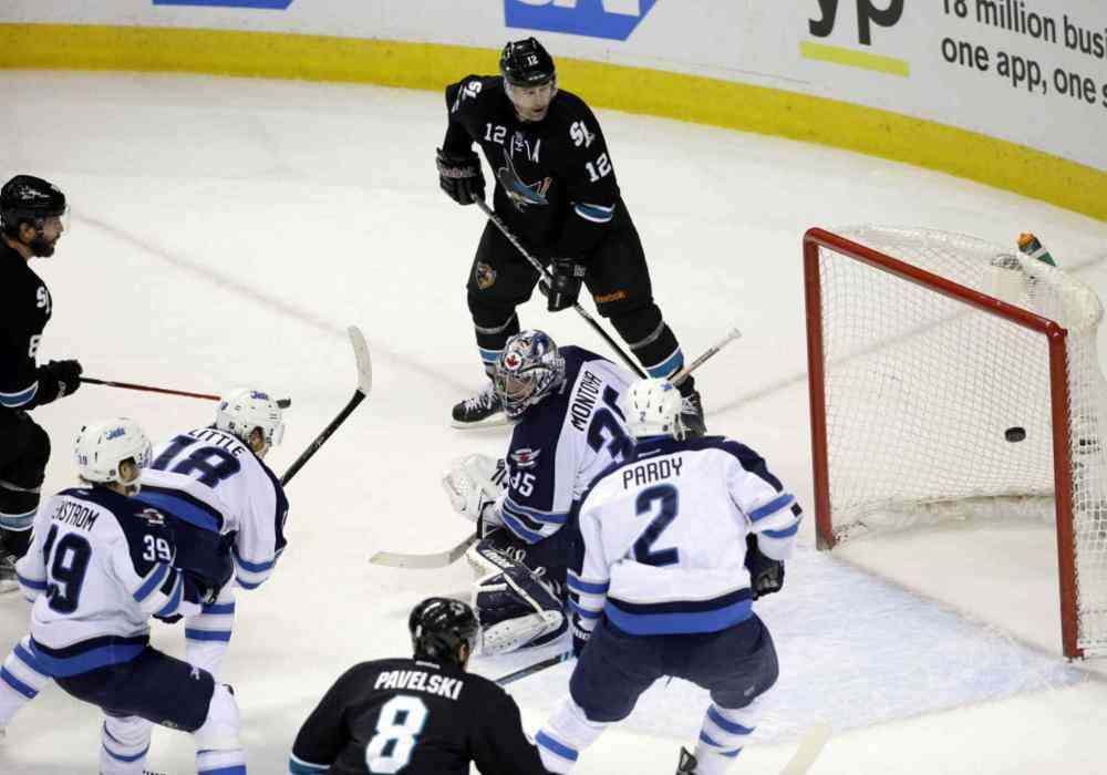 Marcio Jose Sanchez / The Associated Press
San Jose Sharks' Brent Burns, left, scores past Winnipeg Jets goalie Al Montoya, center, during the first period.