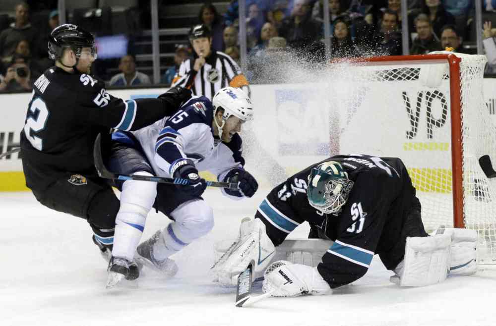 Marcio Jose Sanchez / The Associated Press
San Jose Sharks goalie Antti Niemi, right, stops a shot next to Winnipeg Jets' Matt Halischuk (15) and teammate Matt Irwin (52) during the second period on Thursday.