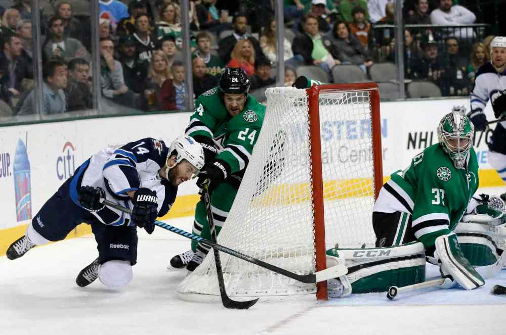 Tony Gutierrez / The Associated Press
Winnipeg Jets' Anthony Peluso (left) dives to take a shot around the net against Dallas Stars goalie Kari Lehtonen (right) as Jordie Benn gives chase.