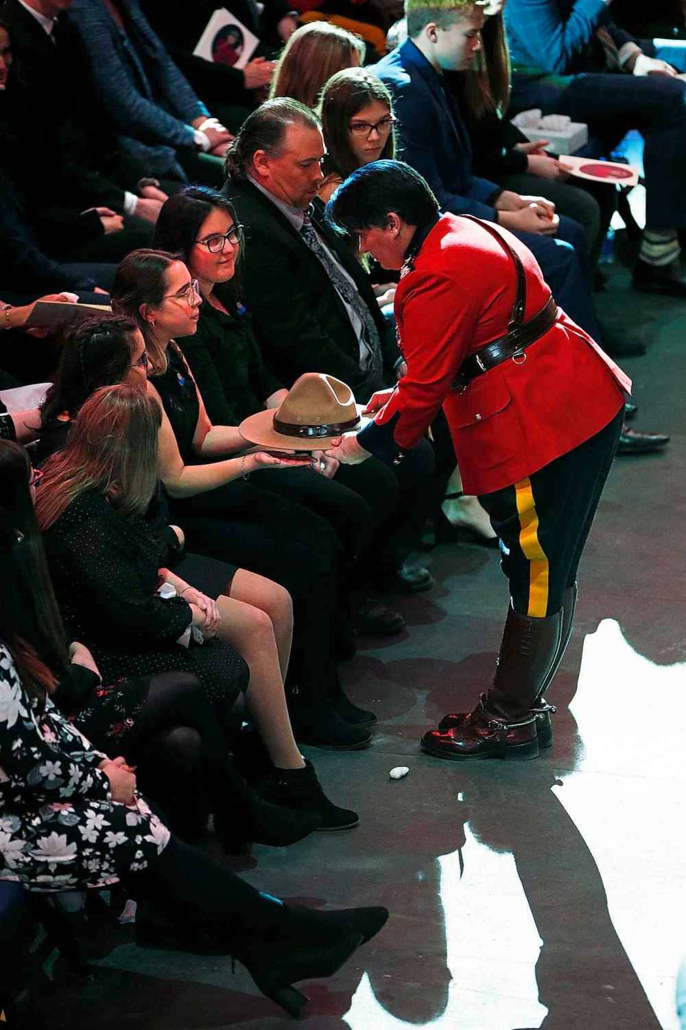 RCMP Assistant Commissioner Jane Maclatchy presents the stetson to Krystal, Chelsie and Caitlyn. (John Woods / The Canadian Press)