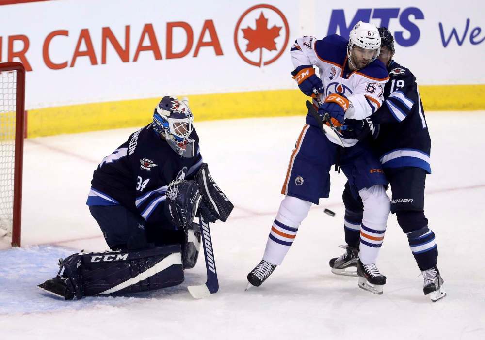 Trevor Hagan / The Canadian Press
Winnipeg Jets goaltender Michael Hutchinson (34) stops a shot as Edmonton Oilers' Benoit Pouliot (67) battles with Nic Petan (19) in front of the net during first period pre-season NHL hockey in Winnipeg, Friday.