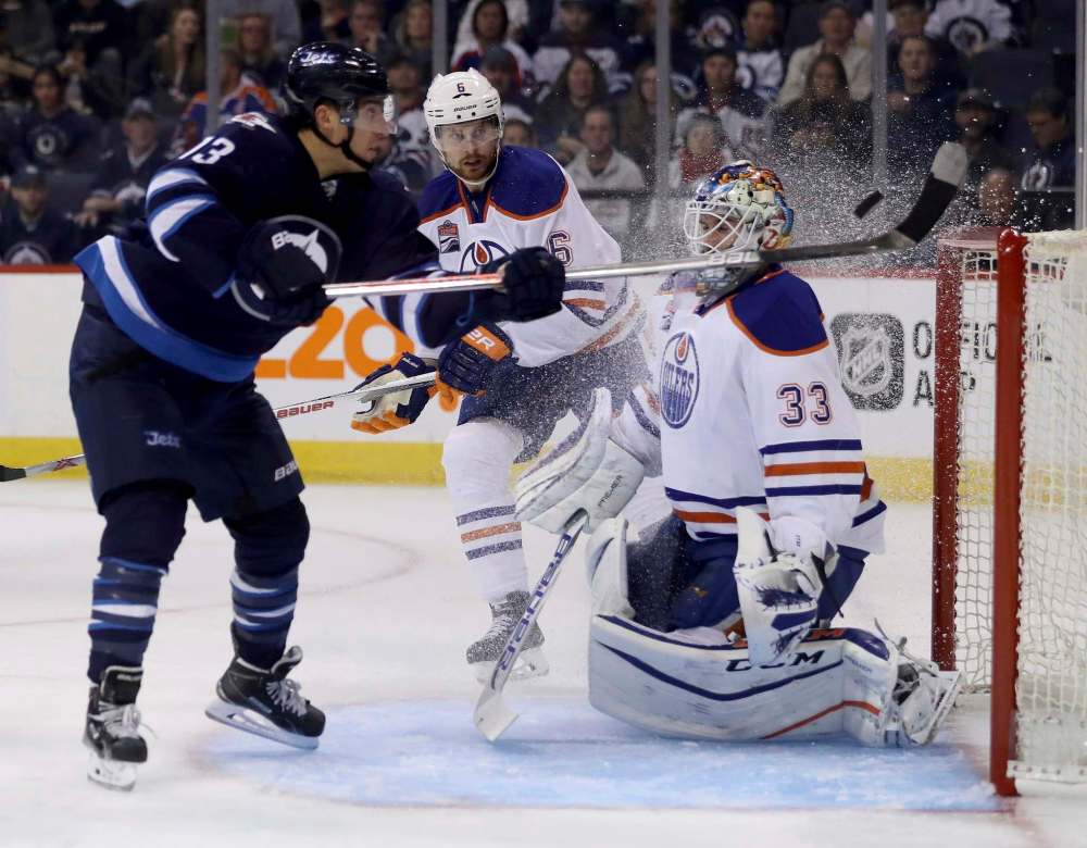 Trevor Hagan / The Canadian Press
Winnipeg Jets' Brandon Tanev (13) knocks the puck into the net behind Edmonton Oilers' goaltender Cam Talbot (33) with Adam Larsson (6) trailing but the goal was waived off due to a high stick during second period pres-eason NHL hockey in Winnipeg, Friday.