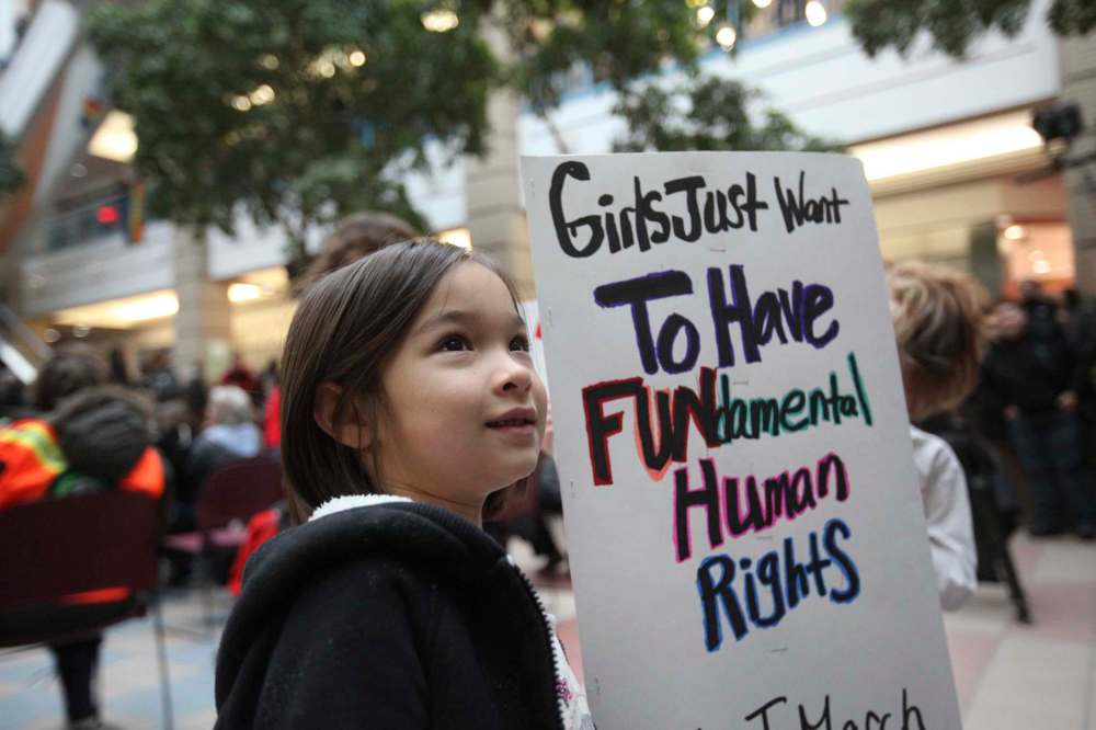 7-year-old Linny holds sign with her mom who joined thousands of others at Portage Place.