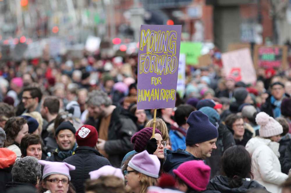 A young woman holds a sign saying, moving forward for Human Rights, as she walks with hundreds of others down Portage Ave. Saturday during the Women's Day March.