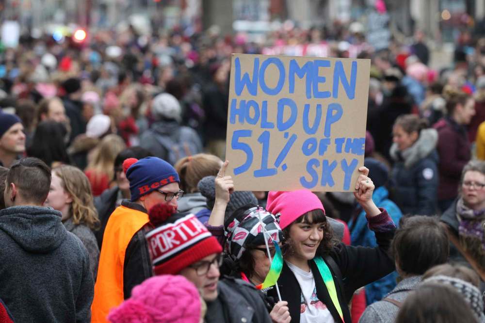 A young woman holds a sign as she makes her way with hundreds of others down Portage Ave. Saturday .