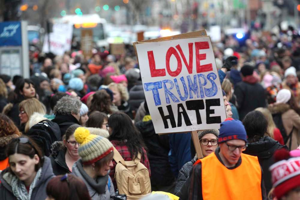A young woman holds a sign that reads, Love Trumps hate, amoung hundreds of marchers as they make their way down Portage Ave. Saturday.
