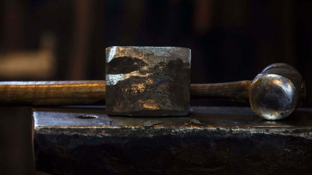 A hammer and anvil fitted with a cutting blade.
