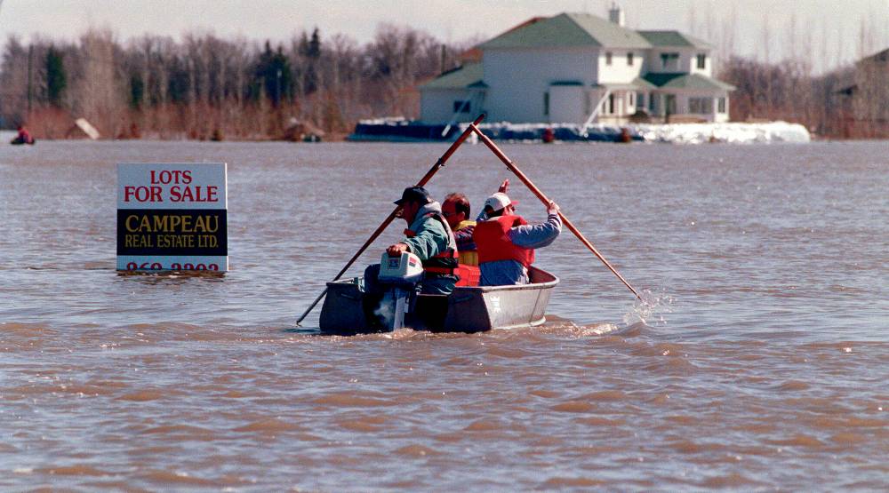 A boat heads toward a diked home in the RM of Ritchot. (Winnipeg Free Press files)