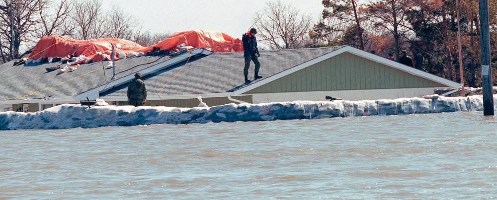 A radio-equipped soldier patrols dikes around a home on St. Mary’s Road south of Winnipeg. (Wayne Glowacki / Winnipeg Free Press files)