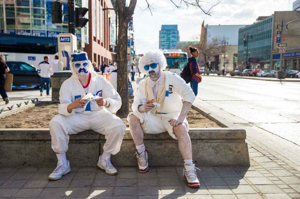 MIKAELA MACKENZIE / WINNIPEG FREE PRESS
Jason Krutish, left, and Aaron Wold eat hot dogs on Portage at Donald Street before the whiteout street party on Monday.