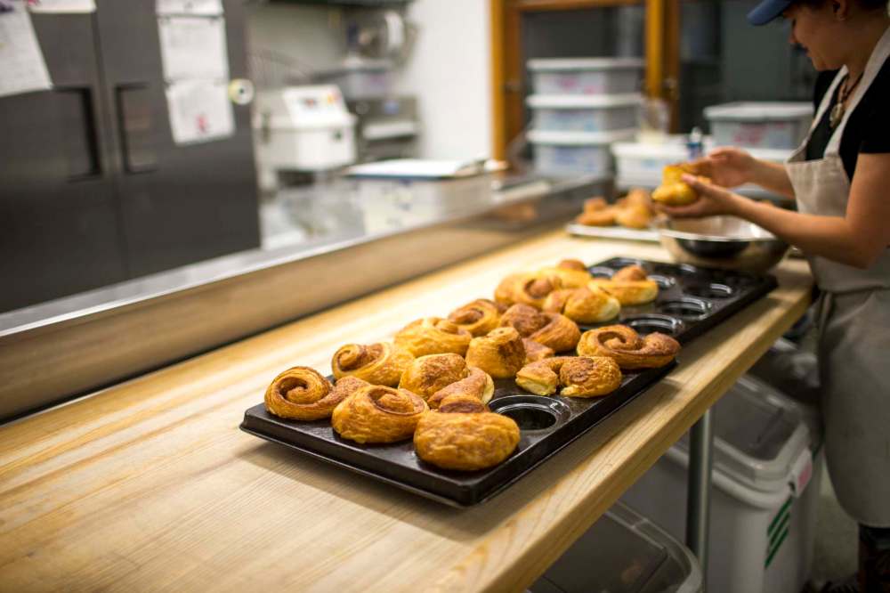 Albanese dips cinnamon buns into sugar.