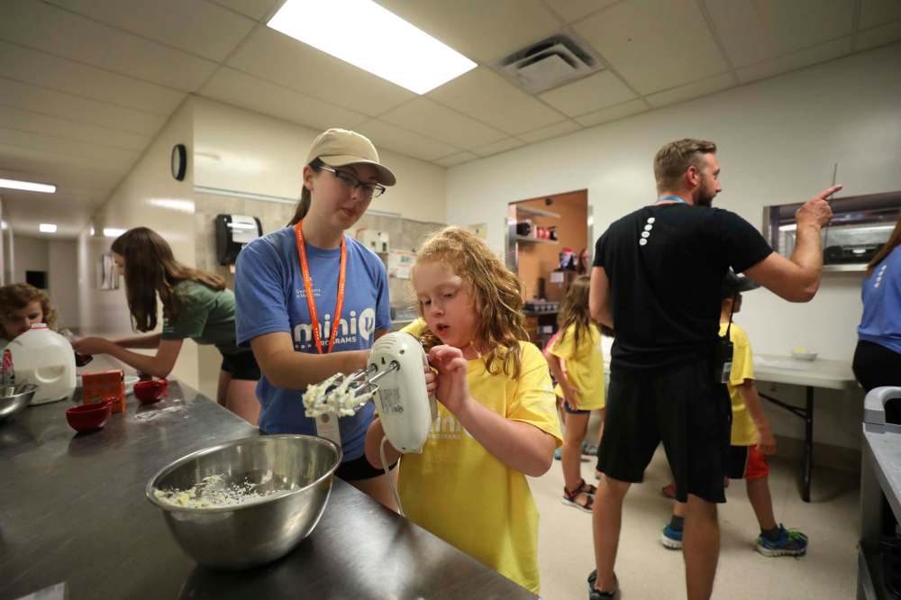 Lauren McKenzie, 7, works on mixing ingredients with the help of Chelsea Guindon.